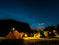 Cozy tents set up in the wilderness, illuminated by a warm campfire