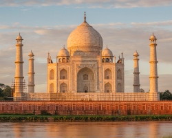 A mesmerizing view of the Taj Mahal standing gracefully along the Yamuna River, reflecting its timeless beauty under the golden light.