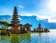 This picturesque image displays a sacred Balinese temple built on the tranquil waters, surrounded by misty mountains and reflecting a peaceful ambiance.