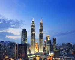 The strikingly lit Petronas Towers rising high against the night sky, with the modern cityscape glowing below.