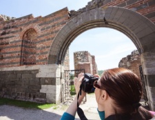 A traveler photographing ancient ruins through a grand archway