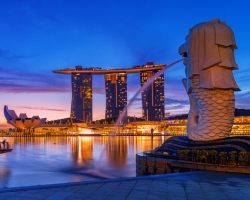 A stunning view of the illuminated Marina Bay Sands Hotel and the iconic Merlion statue standing proudly by the waterfront.