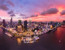 This image paints the scene of a bustling Vietnamese metropolis as the sun sets, casting a colorful glow over the modern cityscape. The lively waterfront and softly lit buildings add a magical allure to the scene.